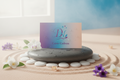 carte cadeau Dhyana Nature représentée sur un galet dans une ambiance zen avec quelques fleurs